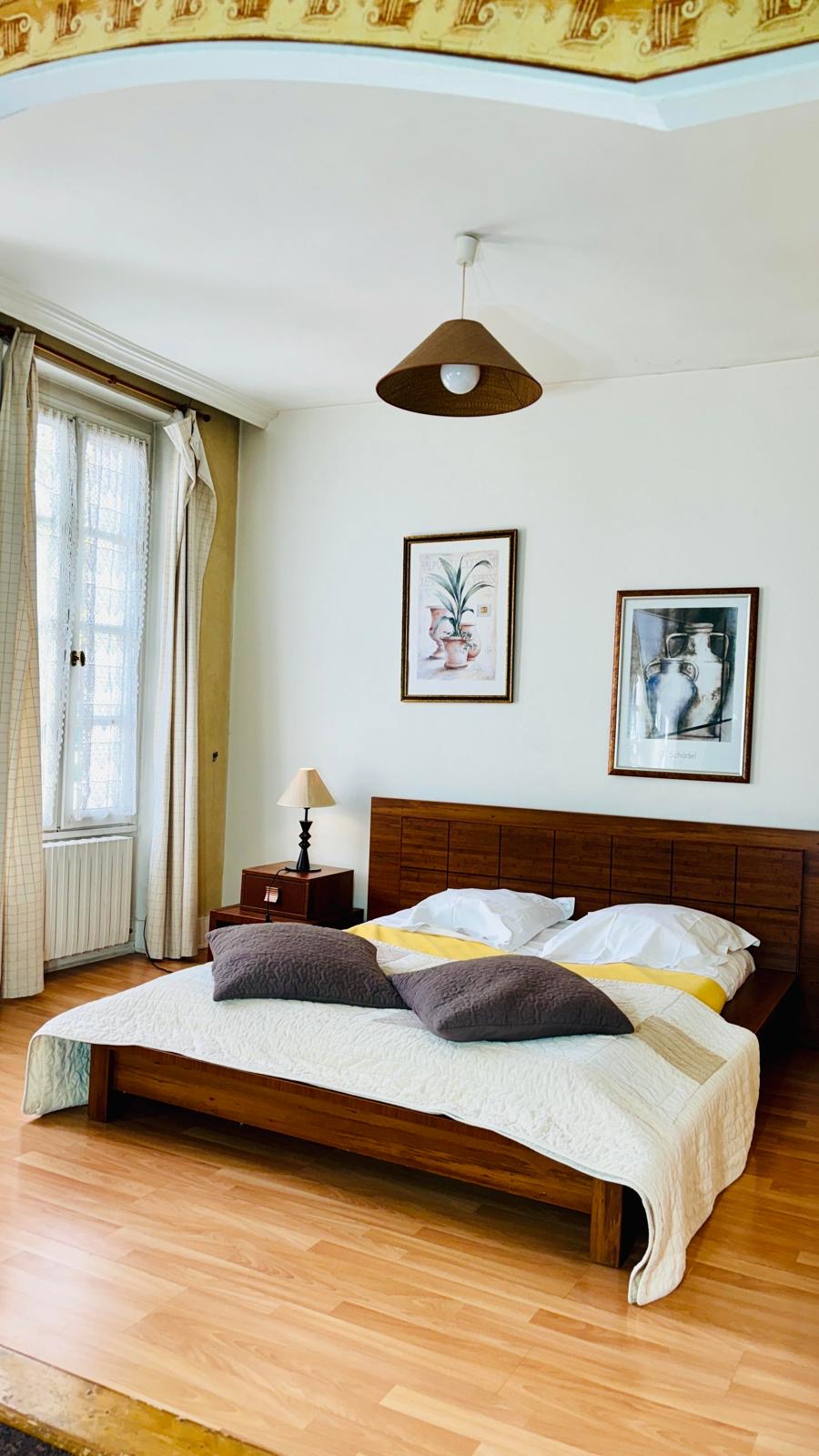Chambre classique avec grande fenêtre et parquet clair